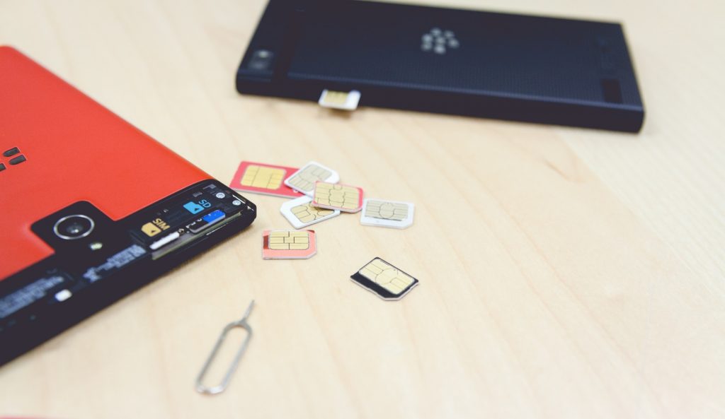 散らばったSIMカードとSIMカードを交換中のスマートフォン